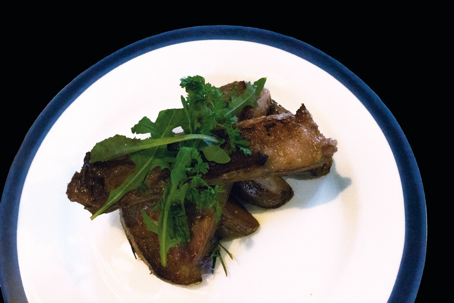 Piatto bianco con pesce grigliato guarnito con erbe fresche e salsa.