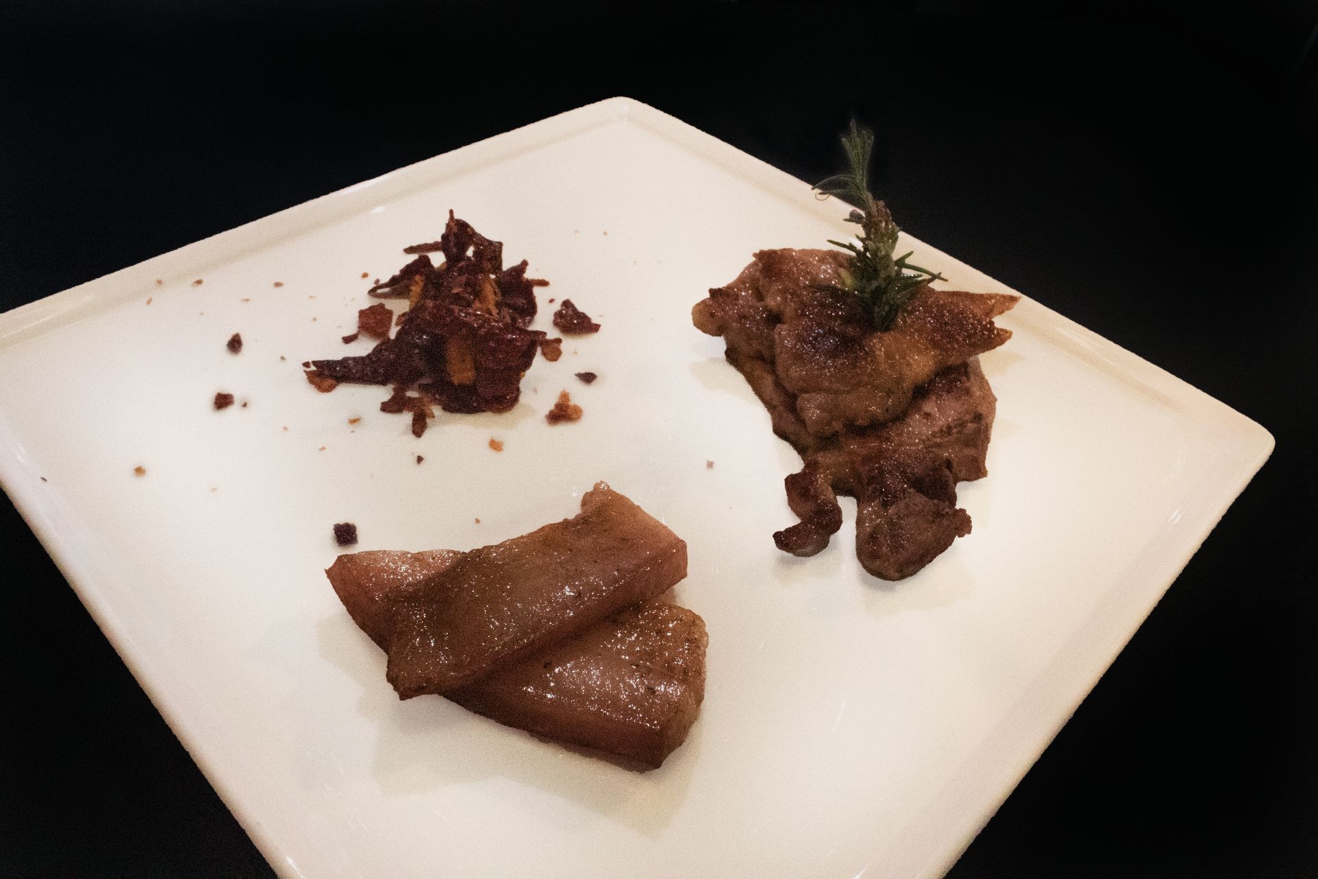 Tre pezzi di carne cotta su un piatto bianco con una piccola guarnizione e salsa.
