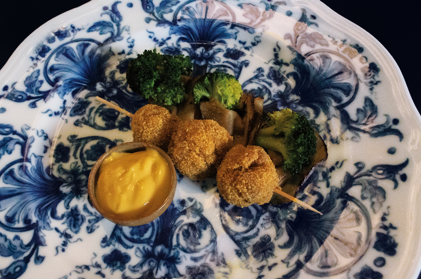 Piatto decorativo blu e bianco con bocconcini fritti e una ciotolina di salsa per intingere.