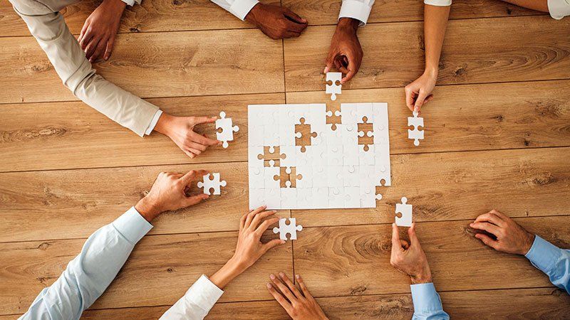 people working together on an all white jigsaw puzzle