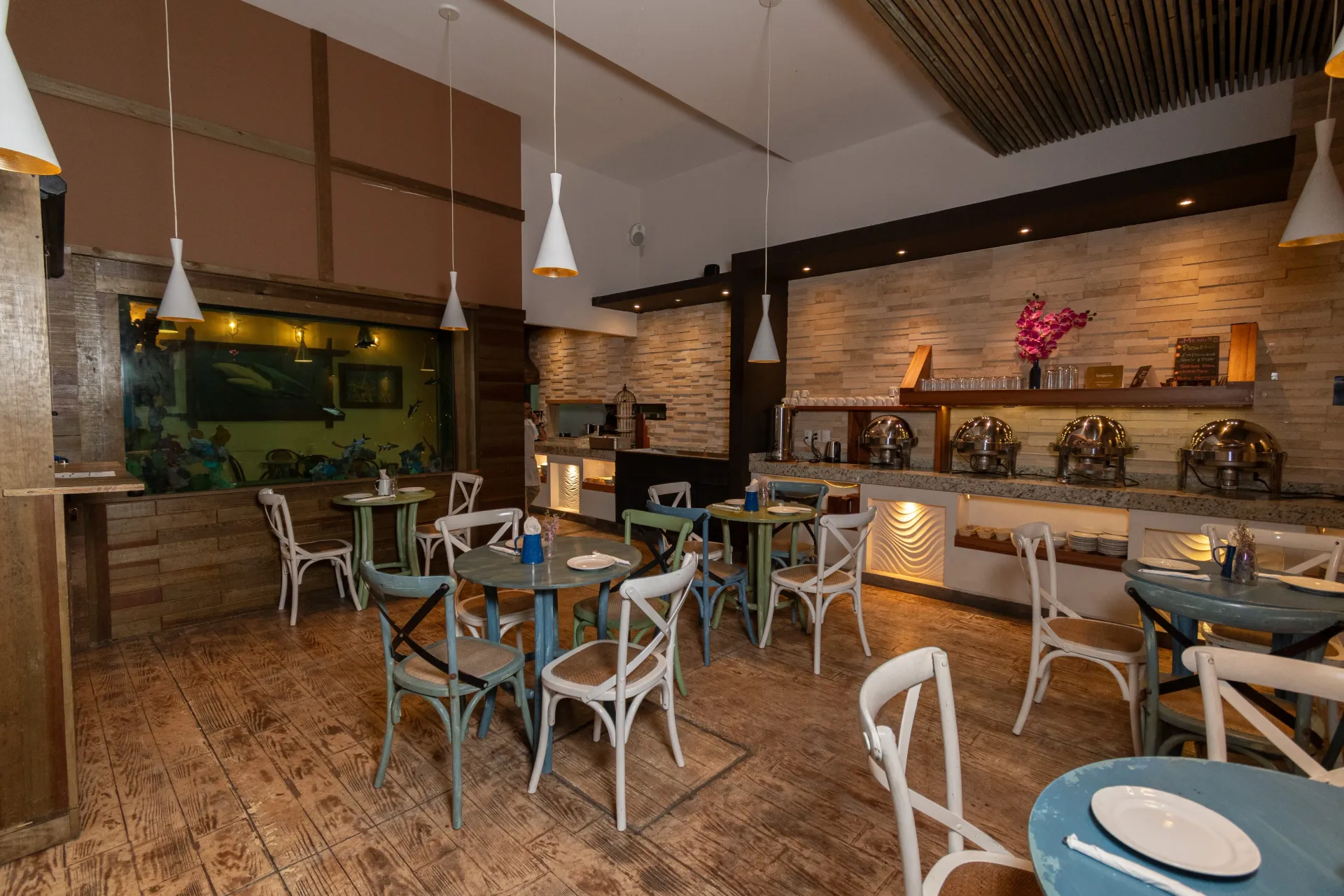 Restaurante  del hotel Clipperton Vercruz con  varias mesas redondas  y sillas alrededor e iluminacion en la habitación