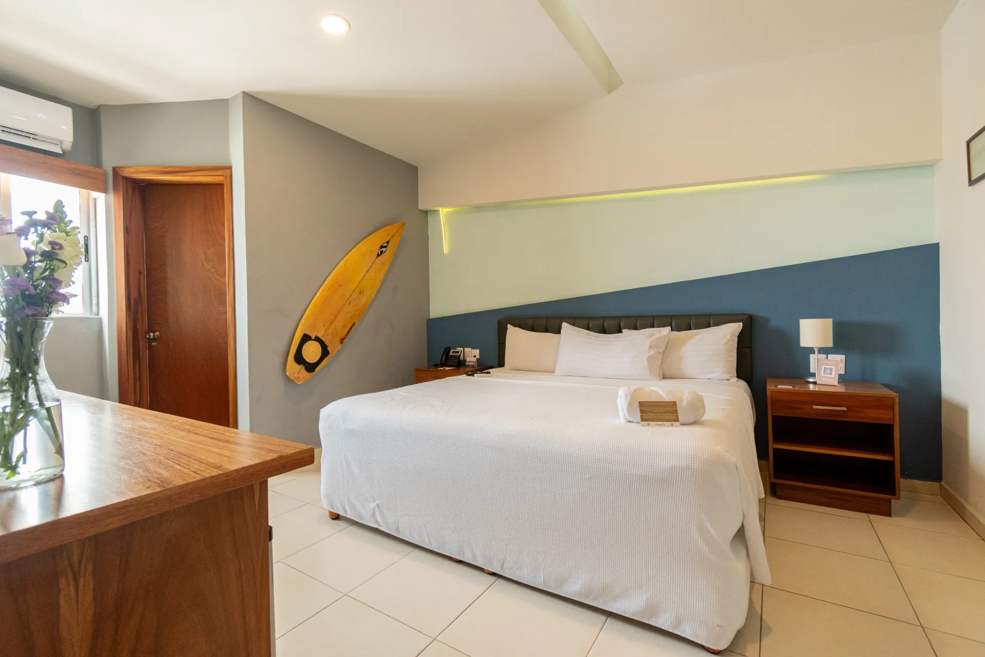 Una habitación de hotel con una cama y una tabla de surf en la pared.