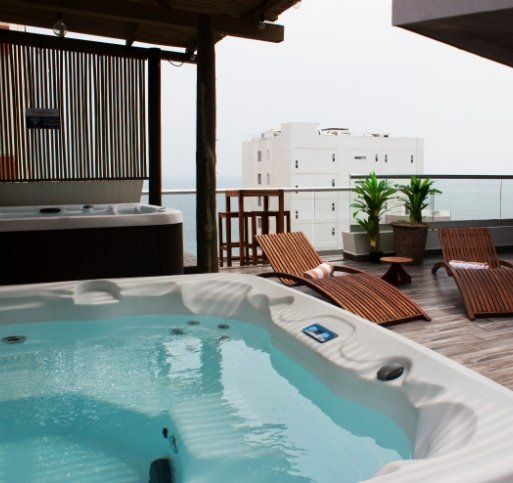 Un jacuzzi en un balcón con vista al mar.