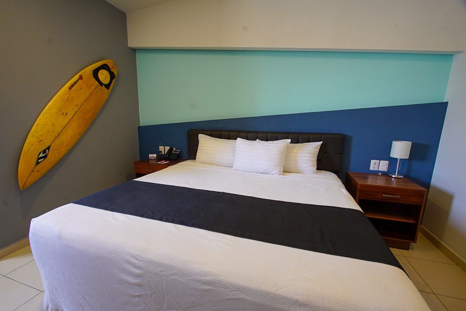 A hotel room with a bed and a surfboard on the wall