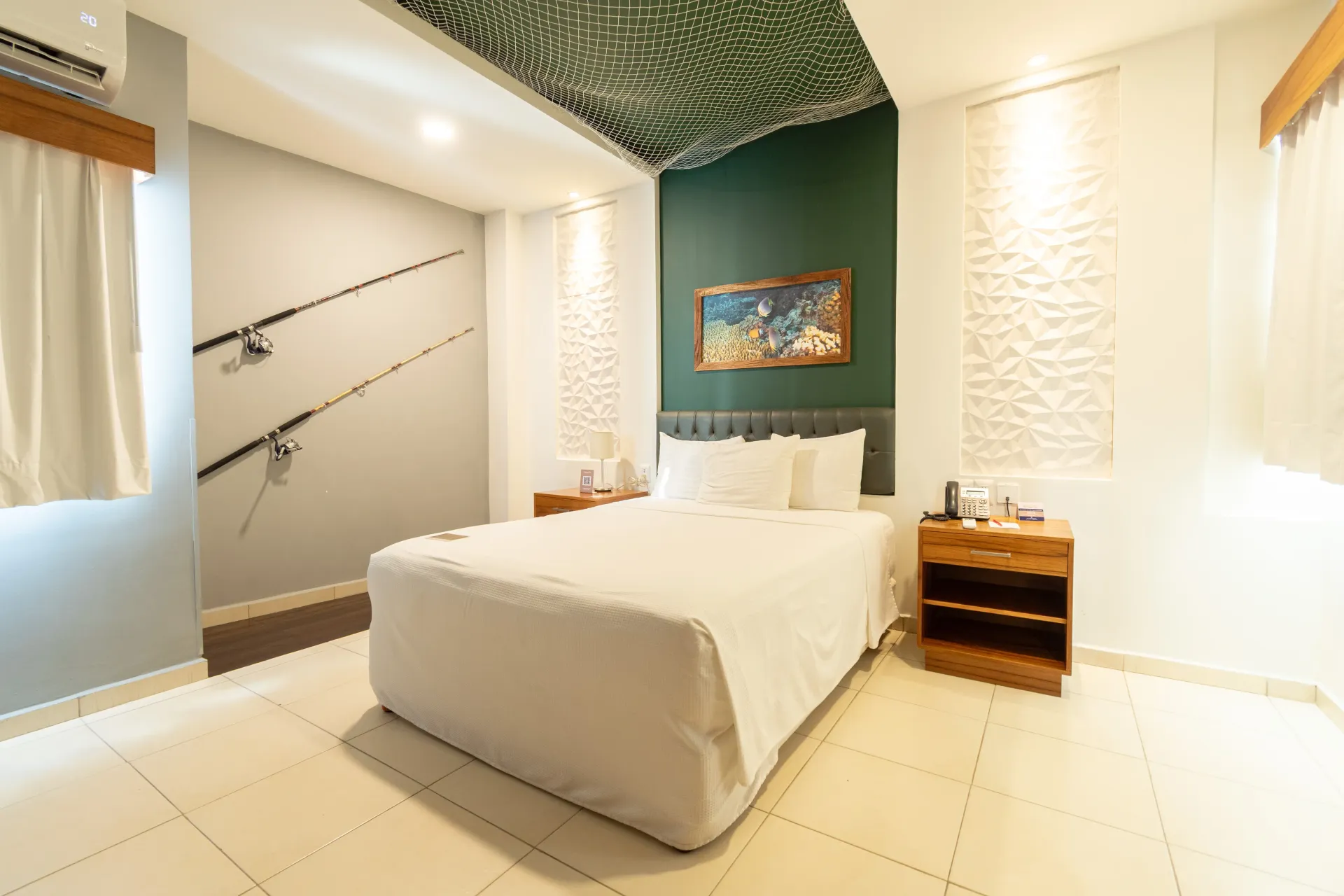 Una habitación de hotel con una cama, dos mesitas de noche, una lámpara y un teléfono.