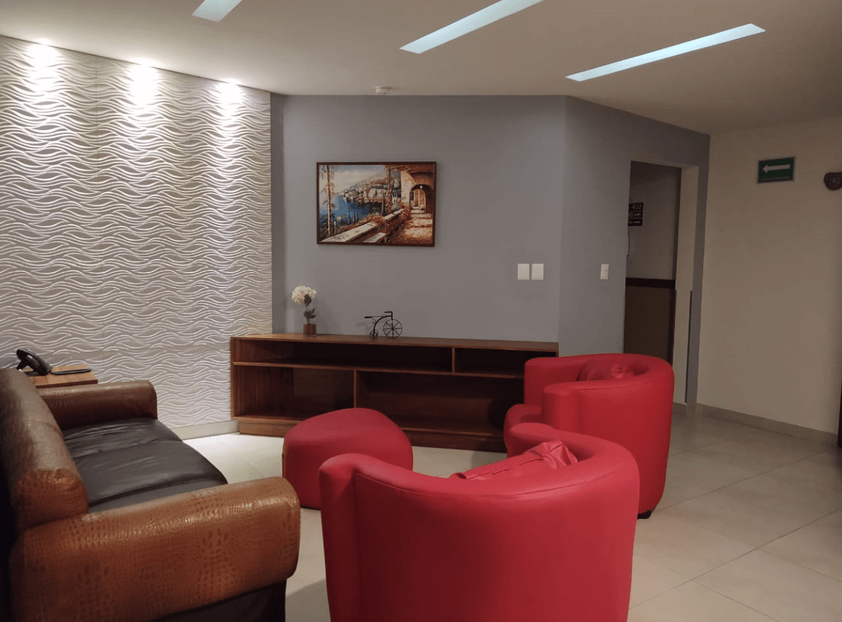 Una sala de estar con un sofá y dos sillas rojas.