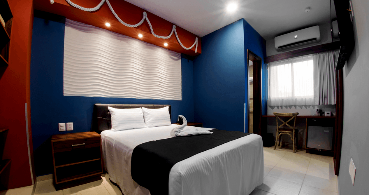 A hotel room with a bed , nightstand , desk and television.