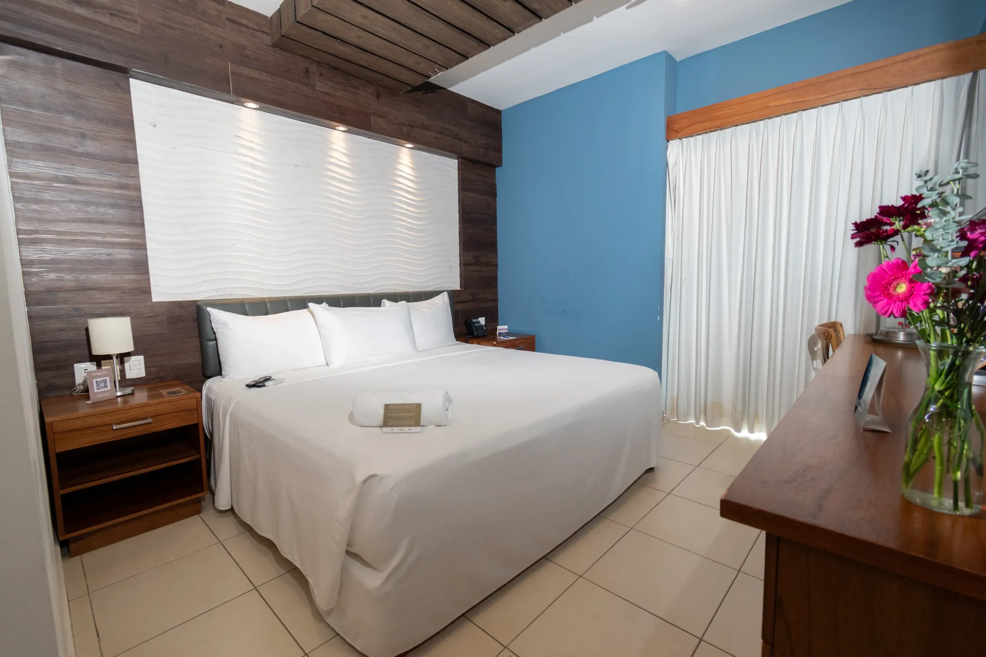 Una habitación de hotel con una cama grande y una cómoda de madera.