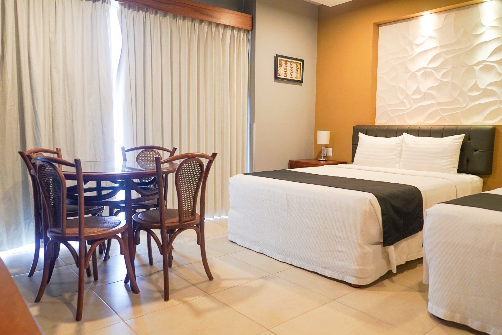 A hotel room with two beds , a table and chairs.