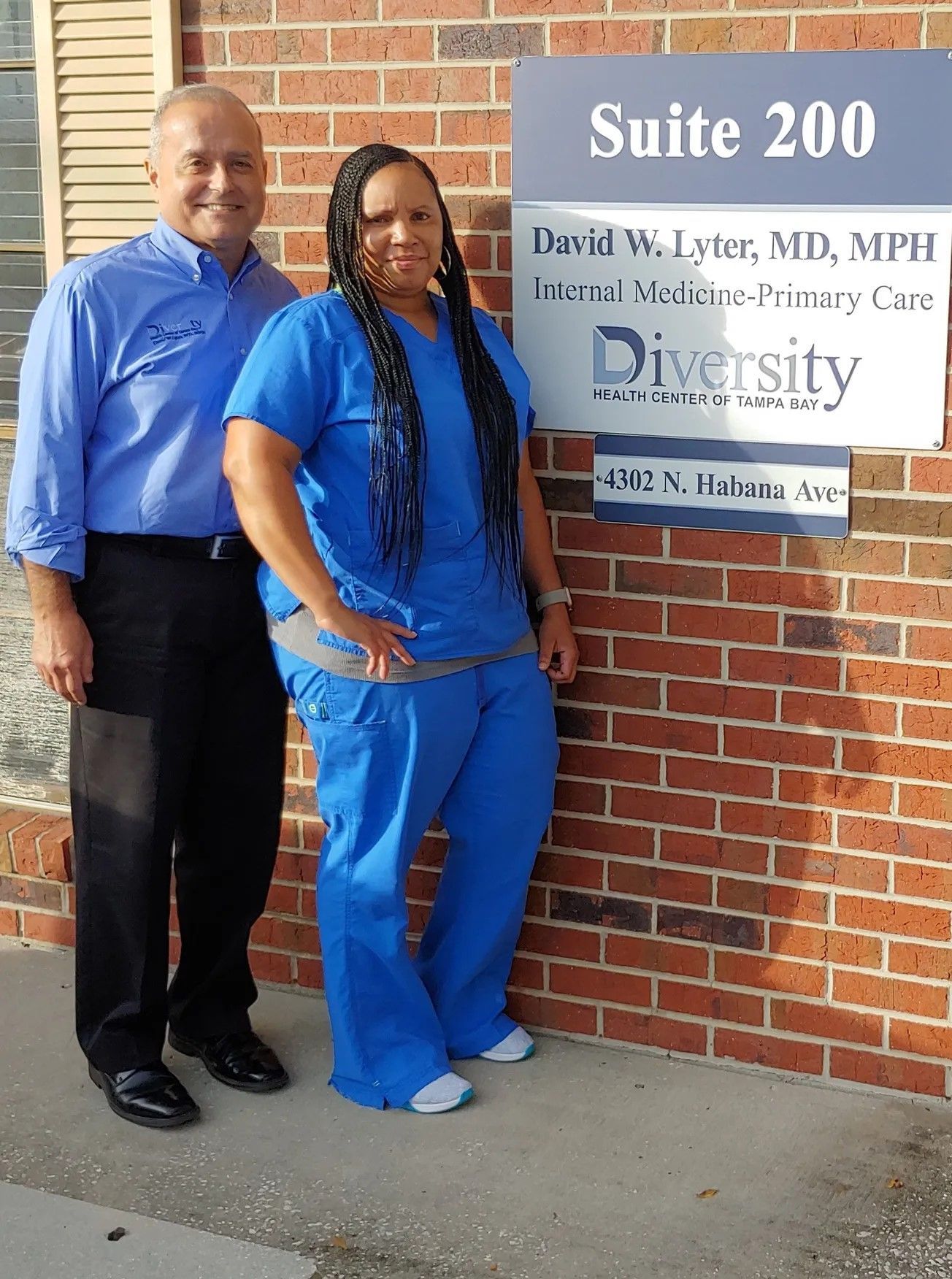 Photo of Dr David W. Lyter, MD, MPH and Shiona Blake, MA outside the office beside their logo sign