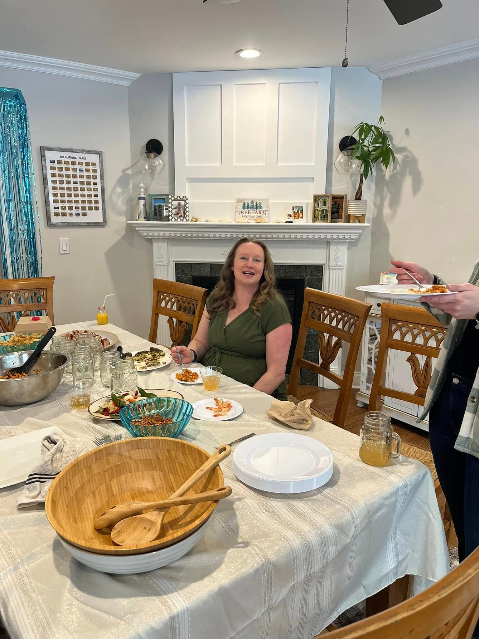 Person seated at a dining table with food and dishes in a bright kitchen-dining room