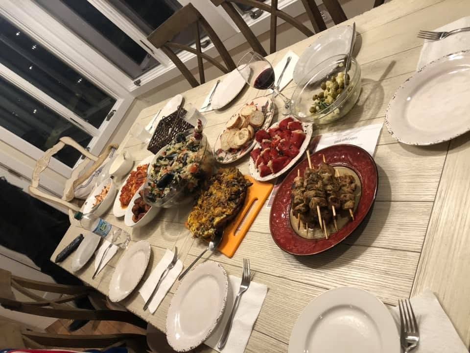 Dinner table with assorted dishes, plates, and glasses set for a meal in a bright dining room