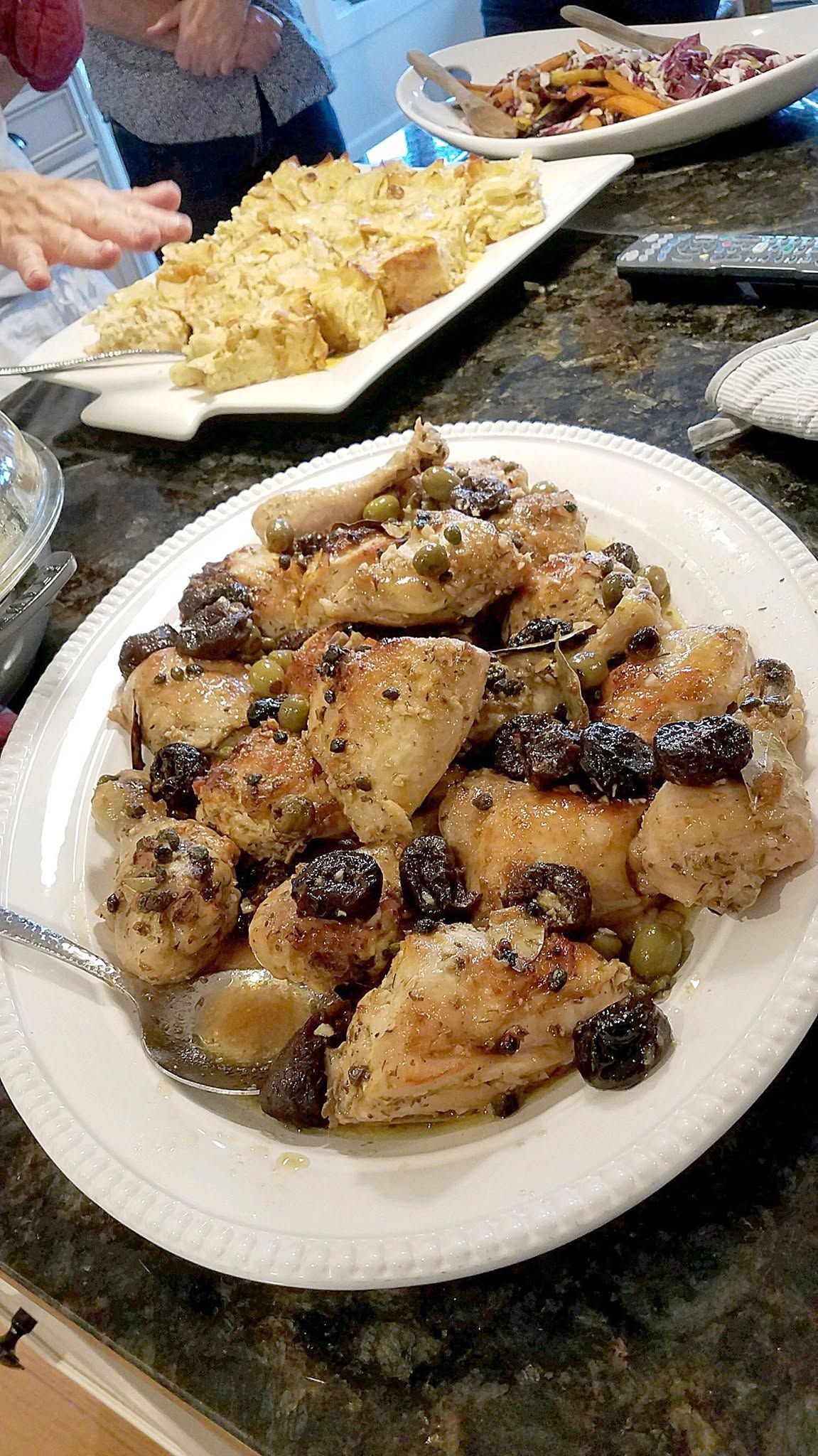Plate of glazed pastries topped with raisins on a kitchen counter, with more dishes in the background