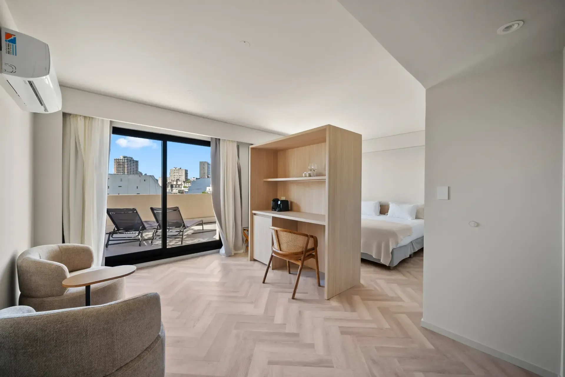 Una habitación de hotel con cama, escritorio, silla y puertas corredizas de vidrio.