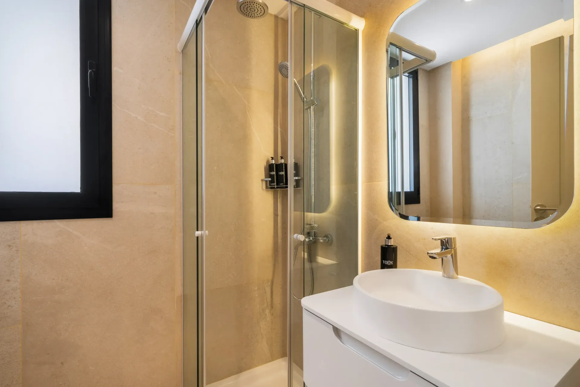 Un baño con lavabo, espejo y cabina de ducha.