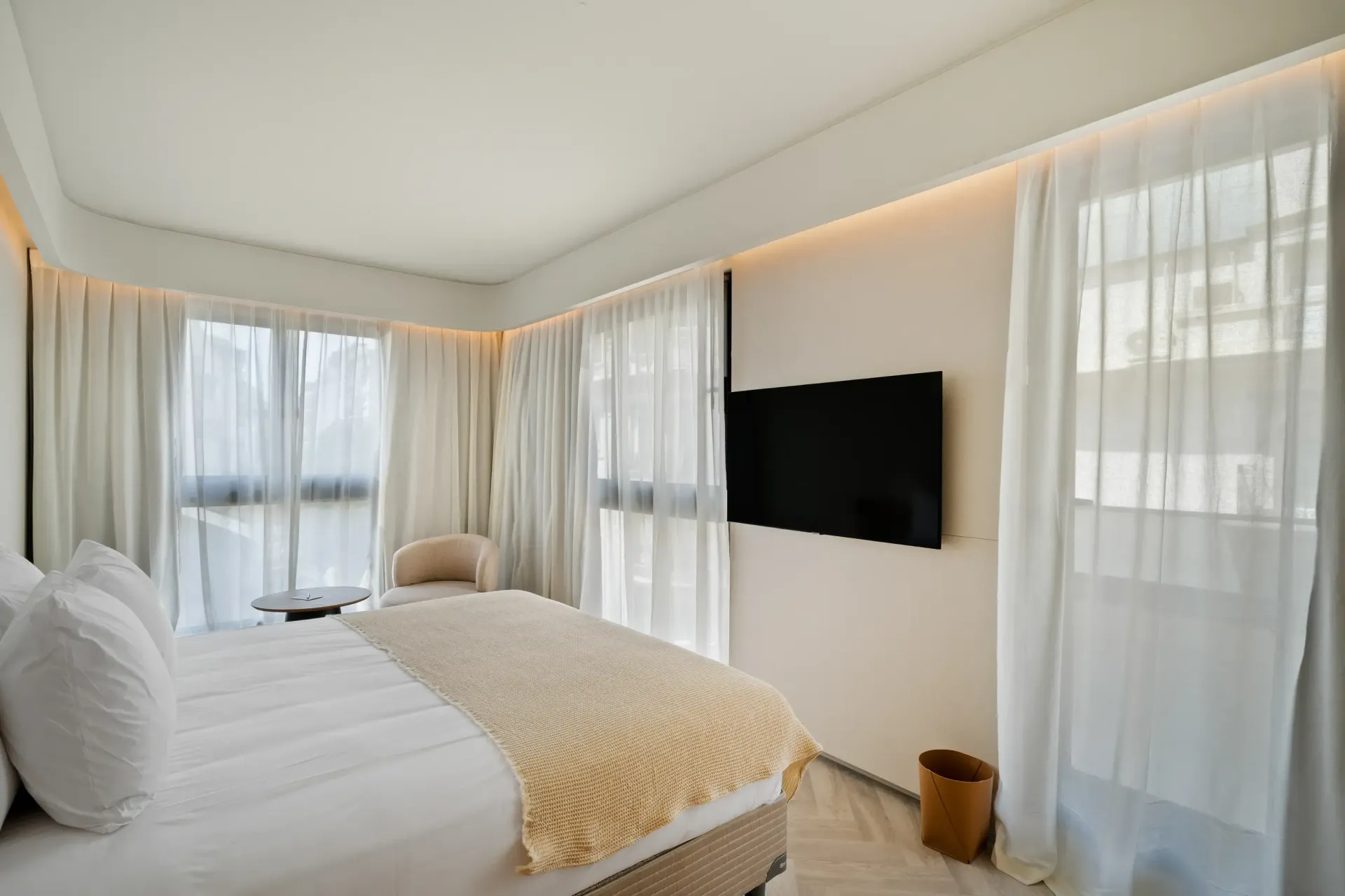 Una habitación de hotel con una cama grande y un televisor de pantalla plana en la pared.