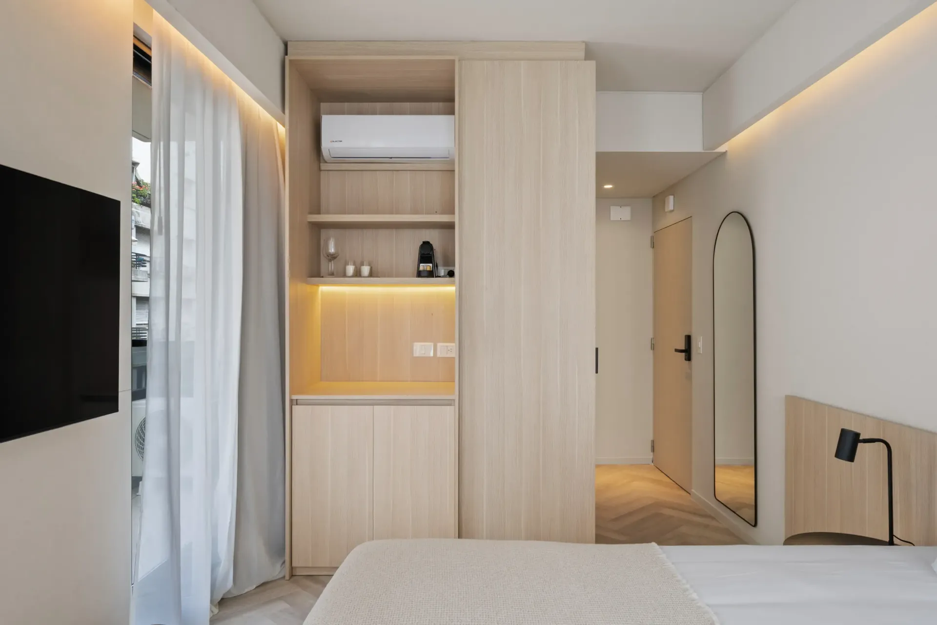 Un dormitorio con una cama, un televisor, un armario y un espejo.