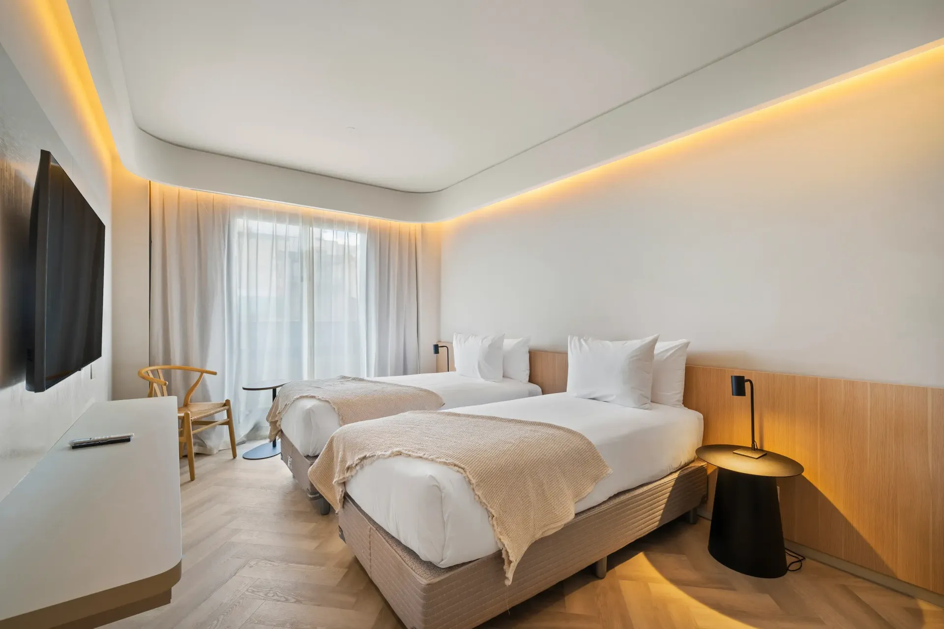 Una habitación de hotel con dos camas y un televisor de pantalla plana.