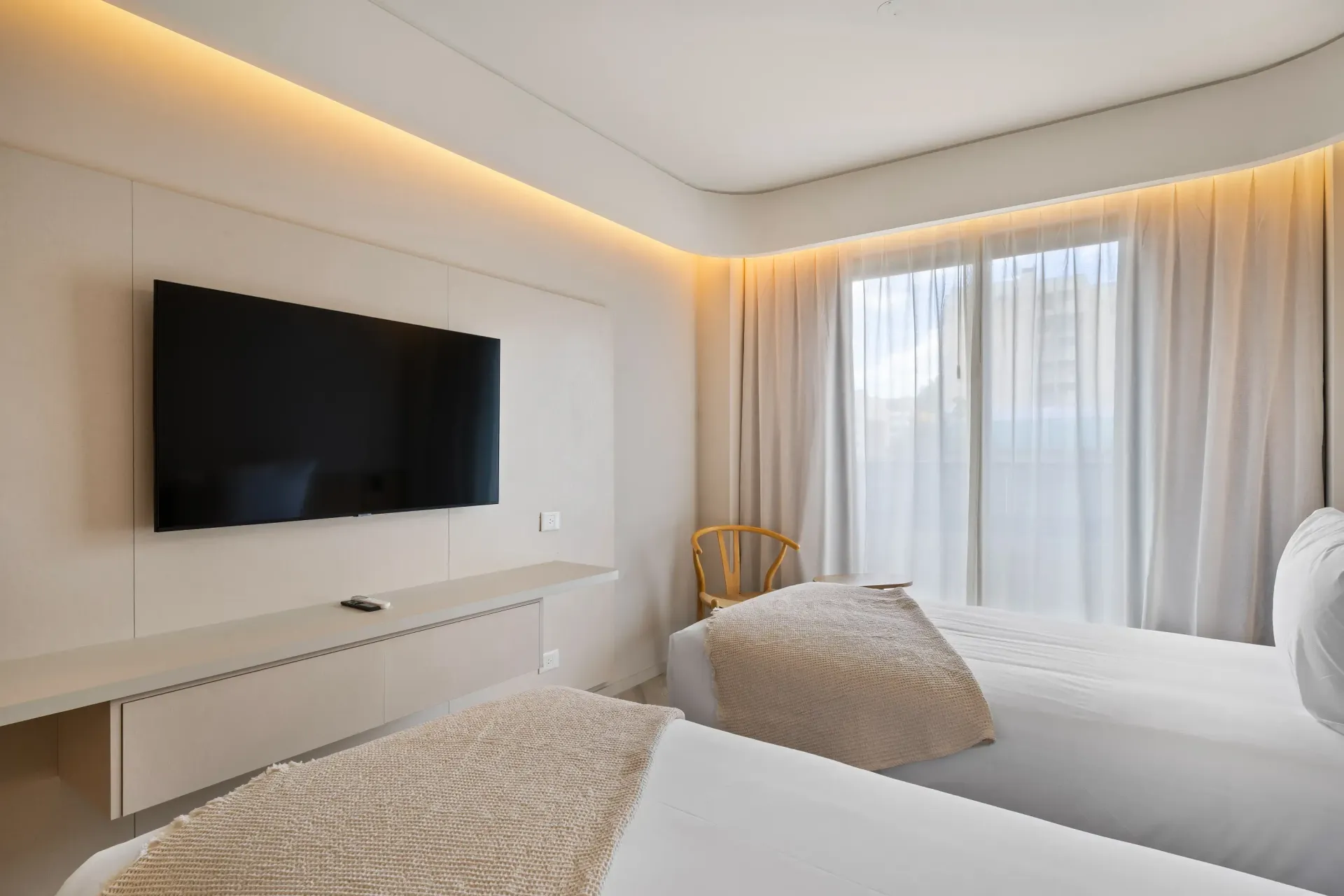 Una habitación de hotel con dos camas y un televisor de pantalla plana en la pared.