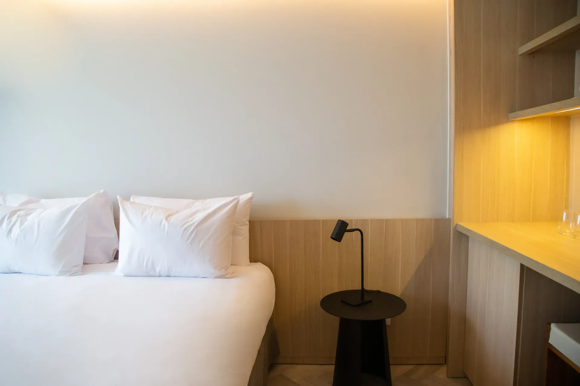 Un dormitorio con cama, mesa, lámpara y escritorio.