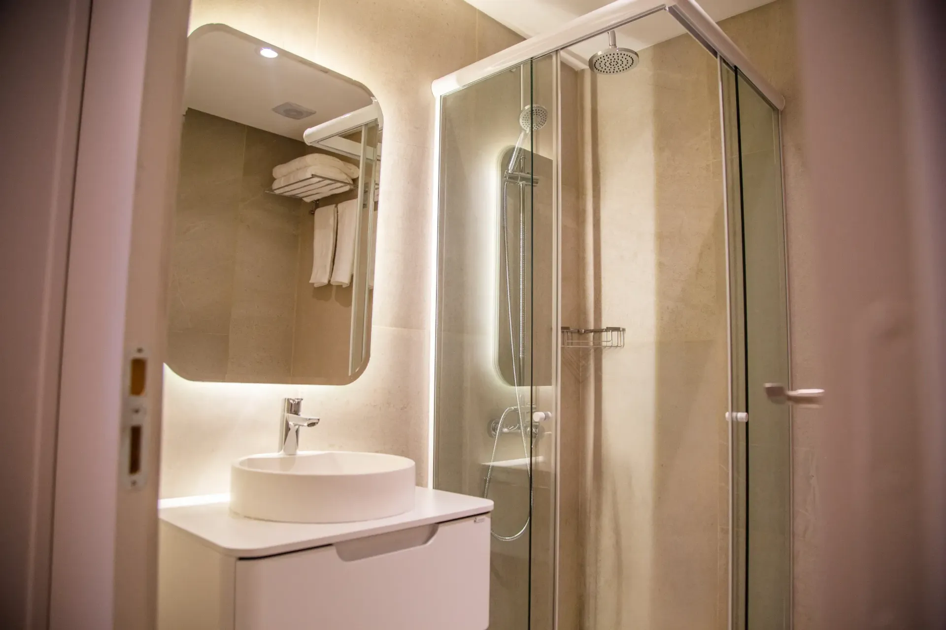 Un baño con lavabo, espejo y cabina de ducha.