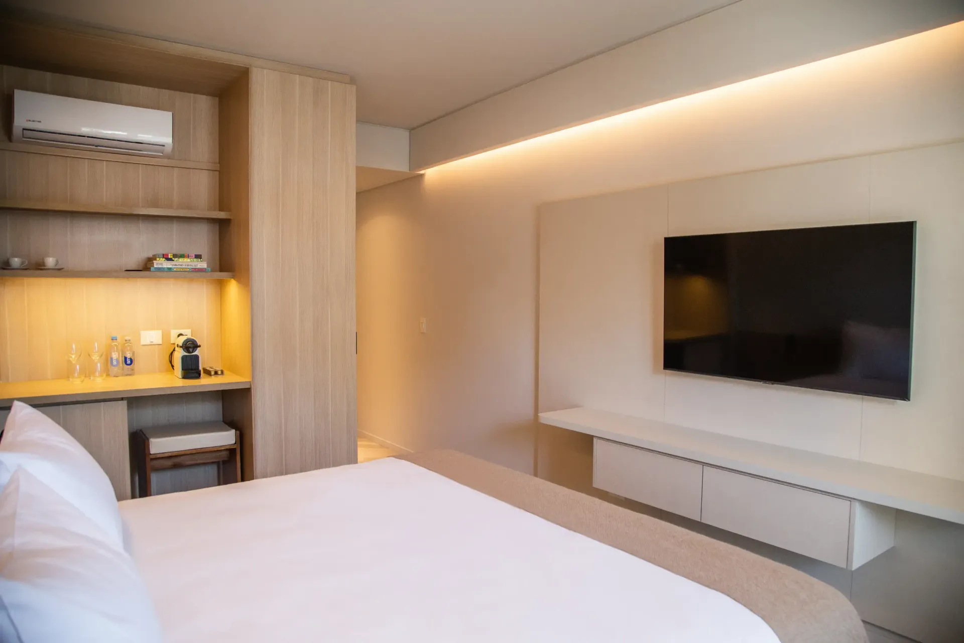 Un dormitorio con una cama grande y un televisor de pantalla plana en la pared.
