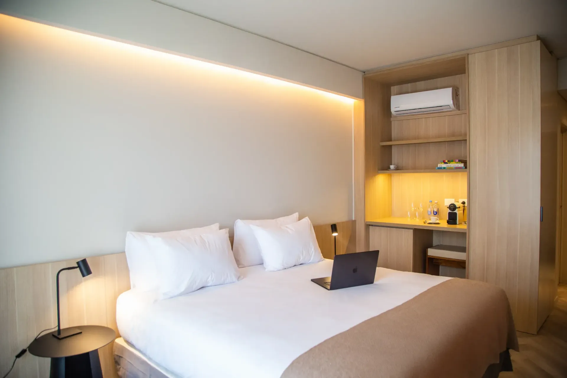 Una habitación de hotel con una cama y un ordenador portátil encima.