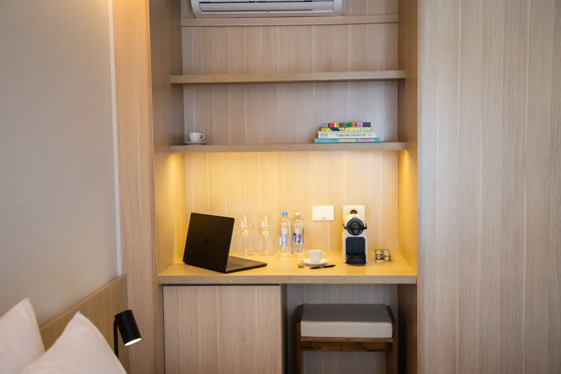 Una habitación de hotel con un escritorio y una computadora portátil encima.