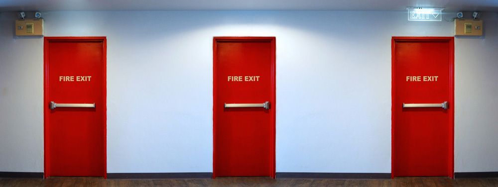 Three Red Fire Exit Doors Aligned in Hallway - Dubbo NSW