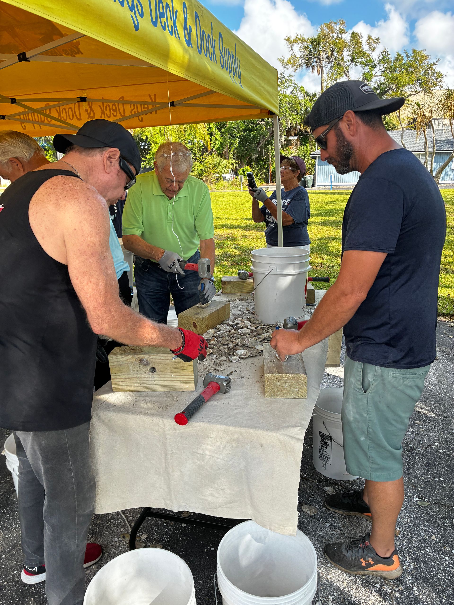People serving food at an outdoor buffet table under a yellow canopy