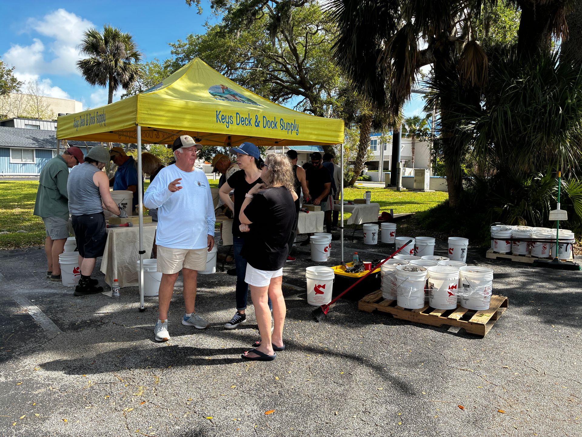 People gathered by a yellow tent at an outdoor food and drink station with coolers and supplies.