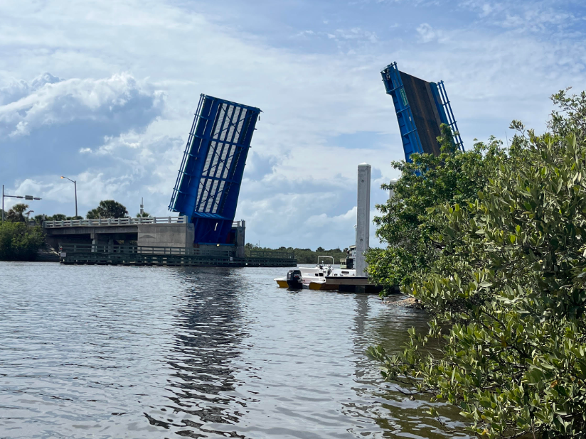 A blue bridge is open over a body of water.