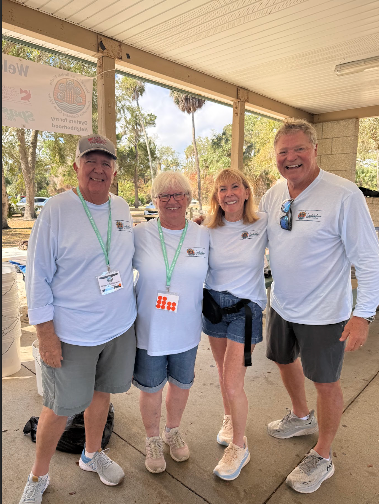 Four people smiling on a covered porch, wearing white shirts and name tags.