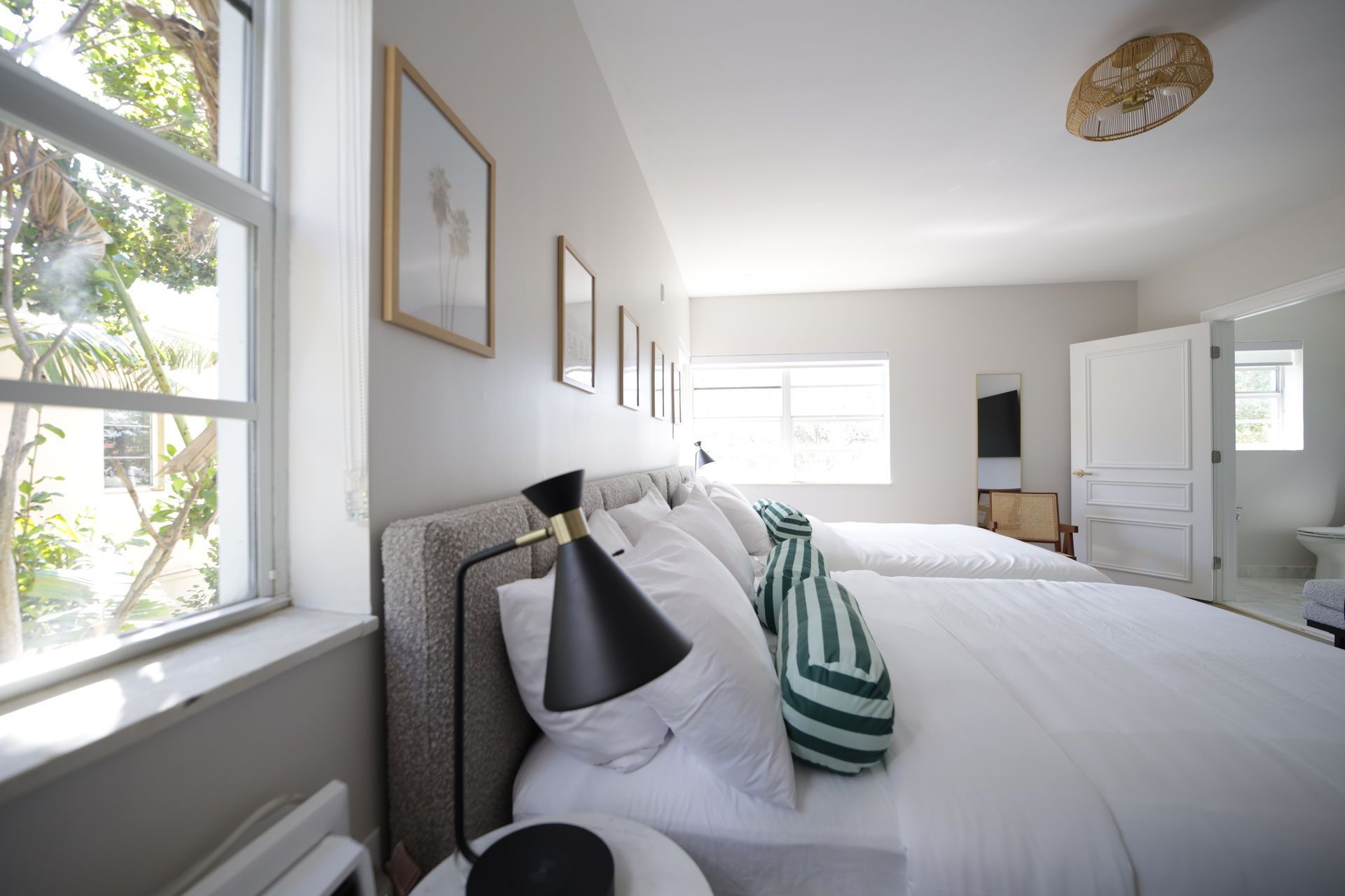 Bedroom with two beds, white linens, large window, and artwork on the wall.