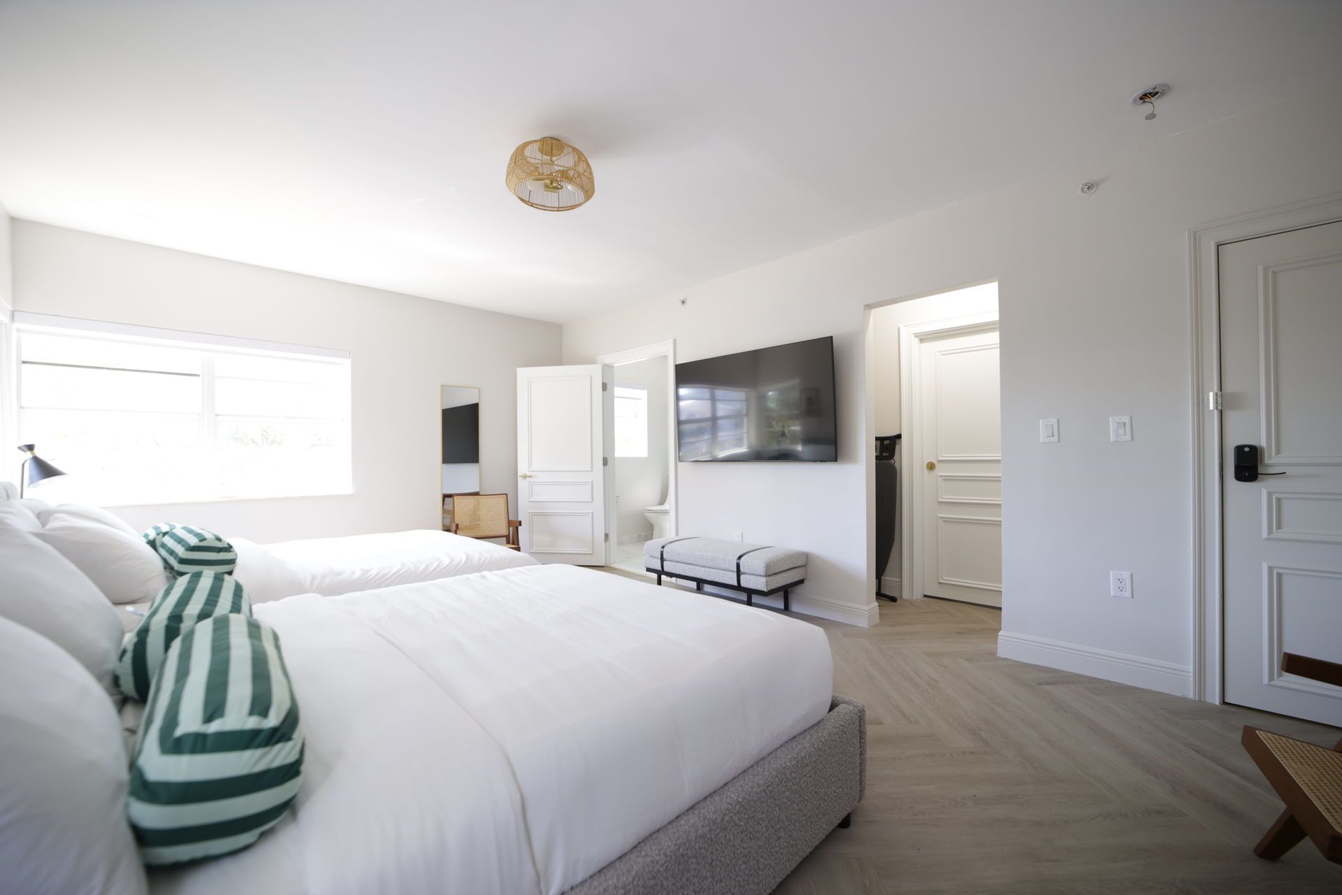 Bedroom with two beds, large TV, white walls, and wooden floors.