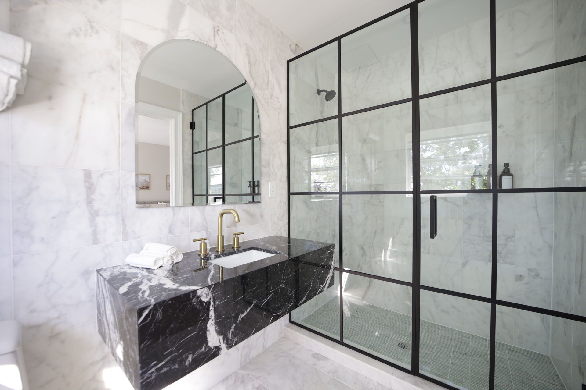 Modern bathroom with black marble vanity and framed glass shower.