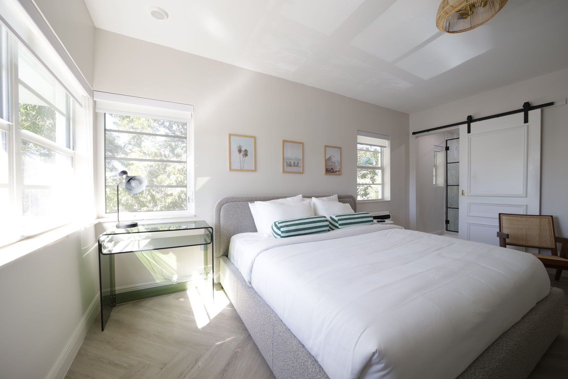 Bright bedroom with a bed, desk, and sliding barn door leading to a bathroom.