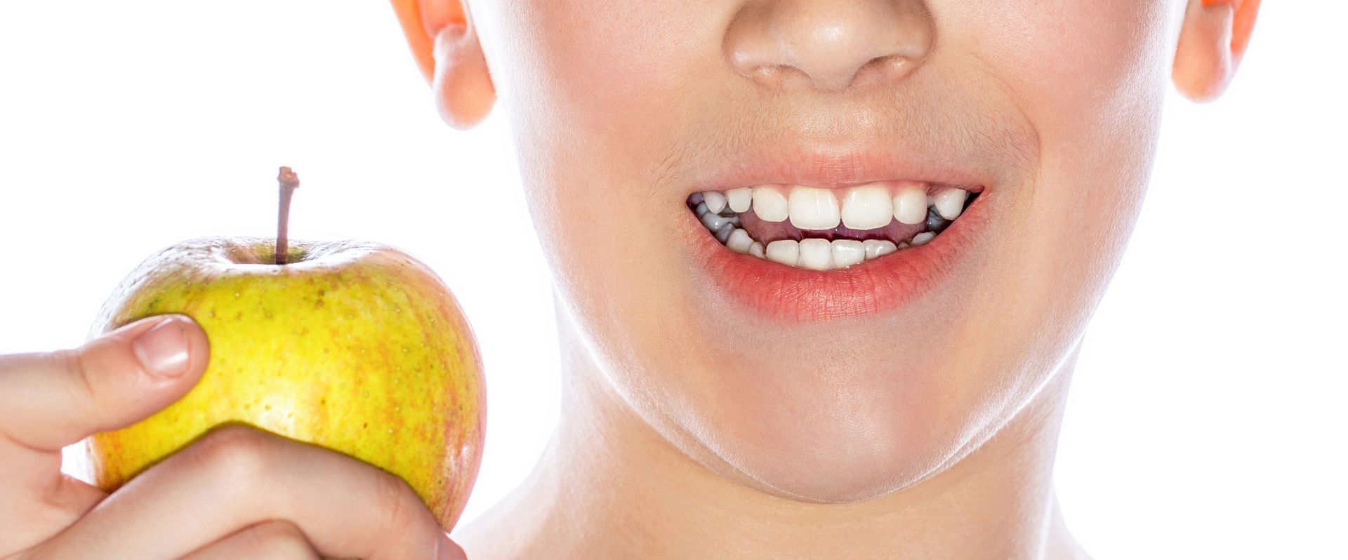 Person holding a yellow apple near a smiling mouth with braces, suggesting dental care or healthy eating