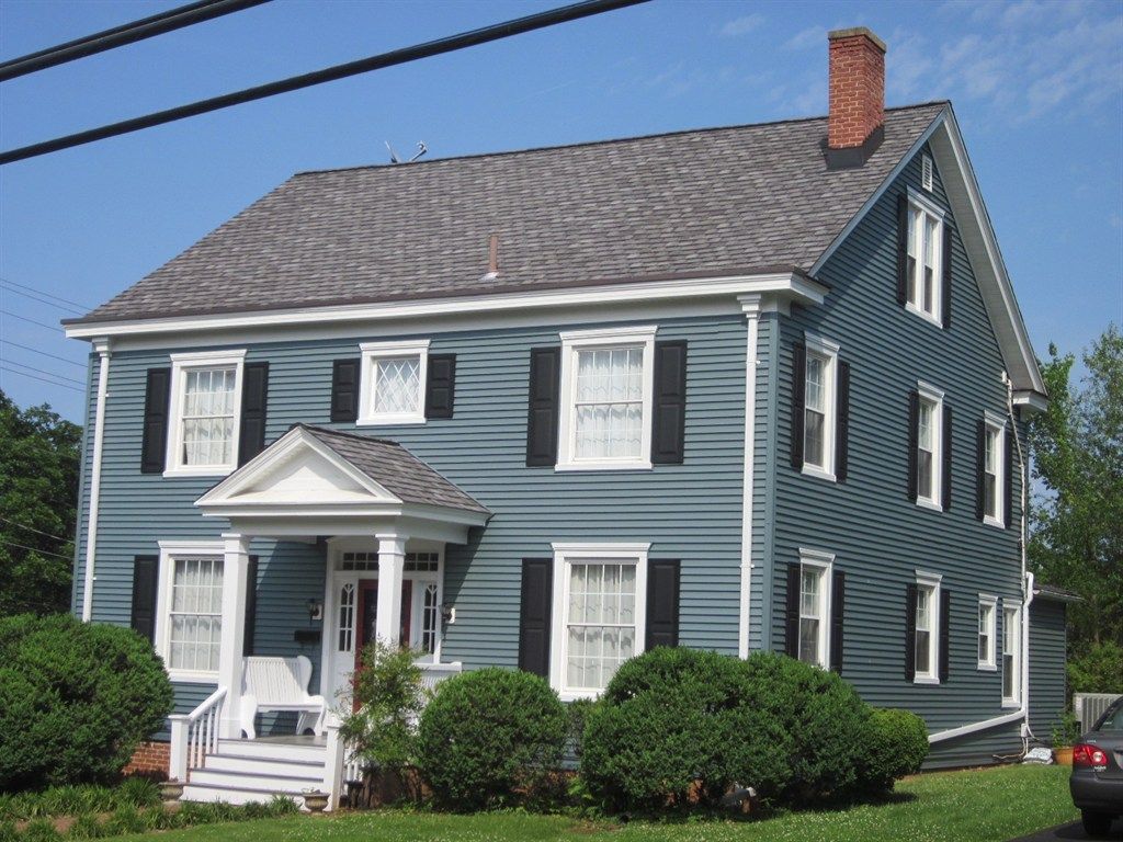 A blue house with black shutters and a car parked in front of it