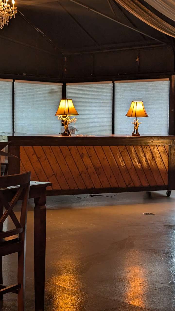 Dimly lit lounge with a wooden counter, two table lamps, and reflective polished floor.