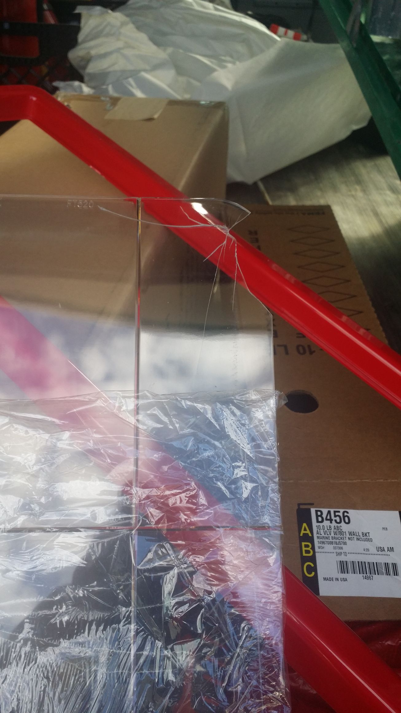 Red metal pallet rack holding wrapped cardboard boxes in a warehouse.