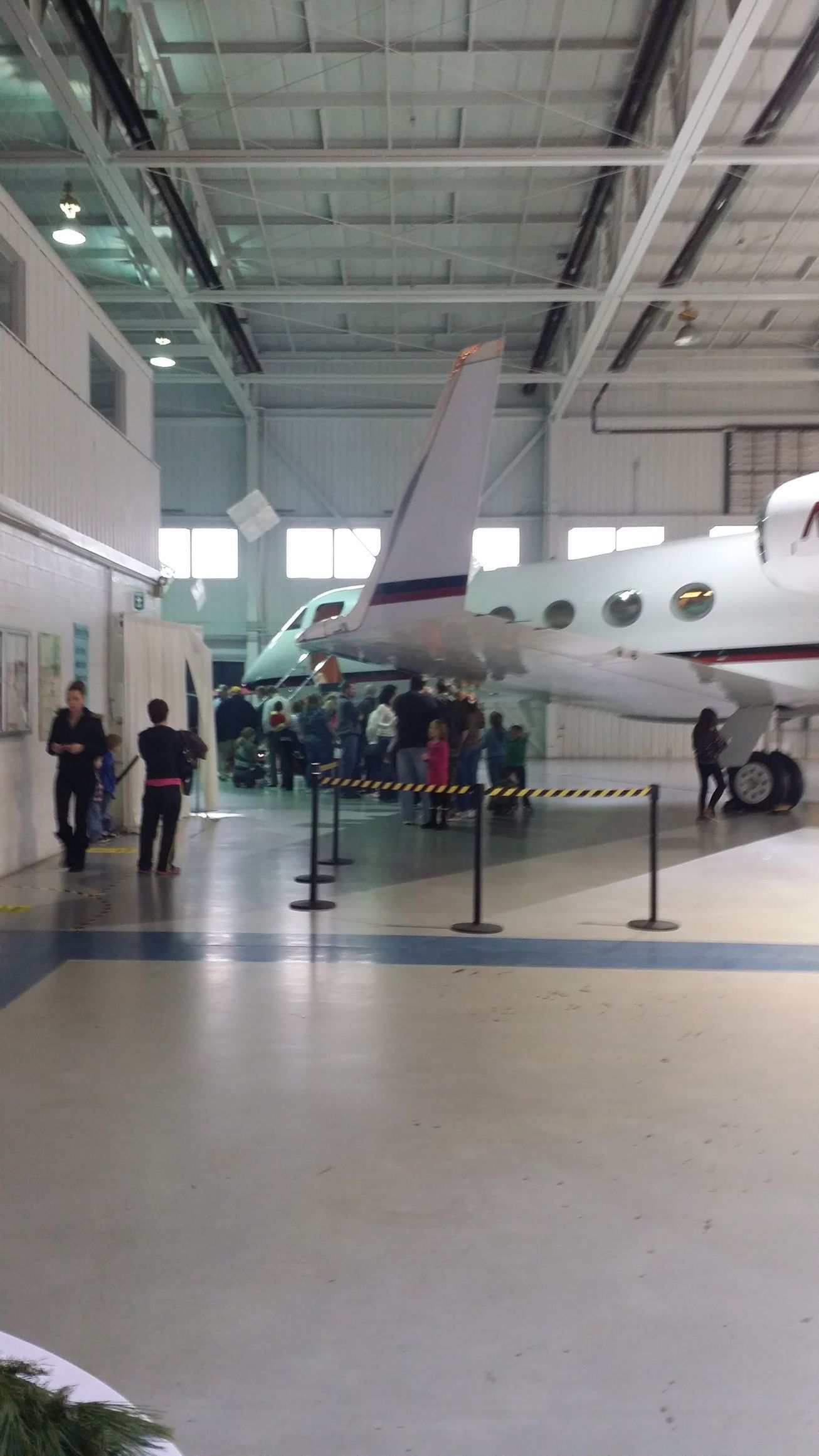 Aircraft on display in a museum hangar, with visitors standing nearby behind ropes.