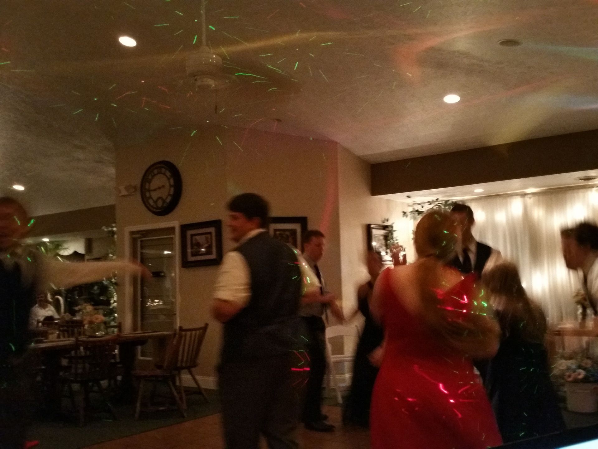 People dancing at an indoor party with warm lights and a red dress in the foreground