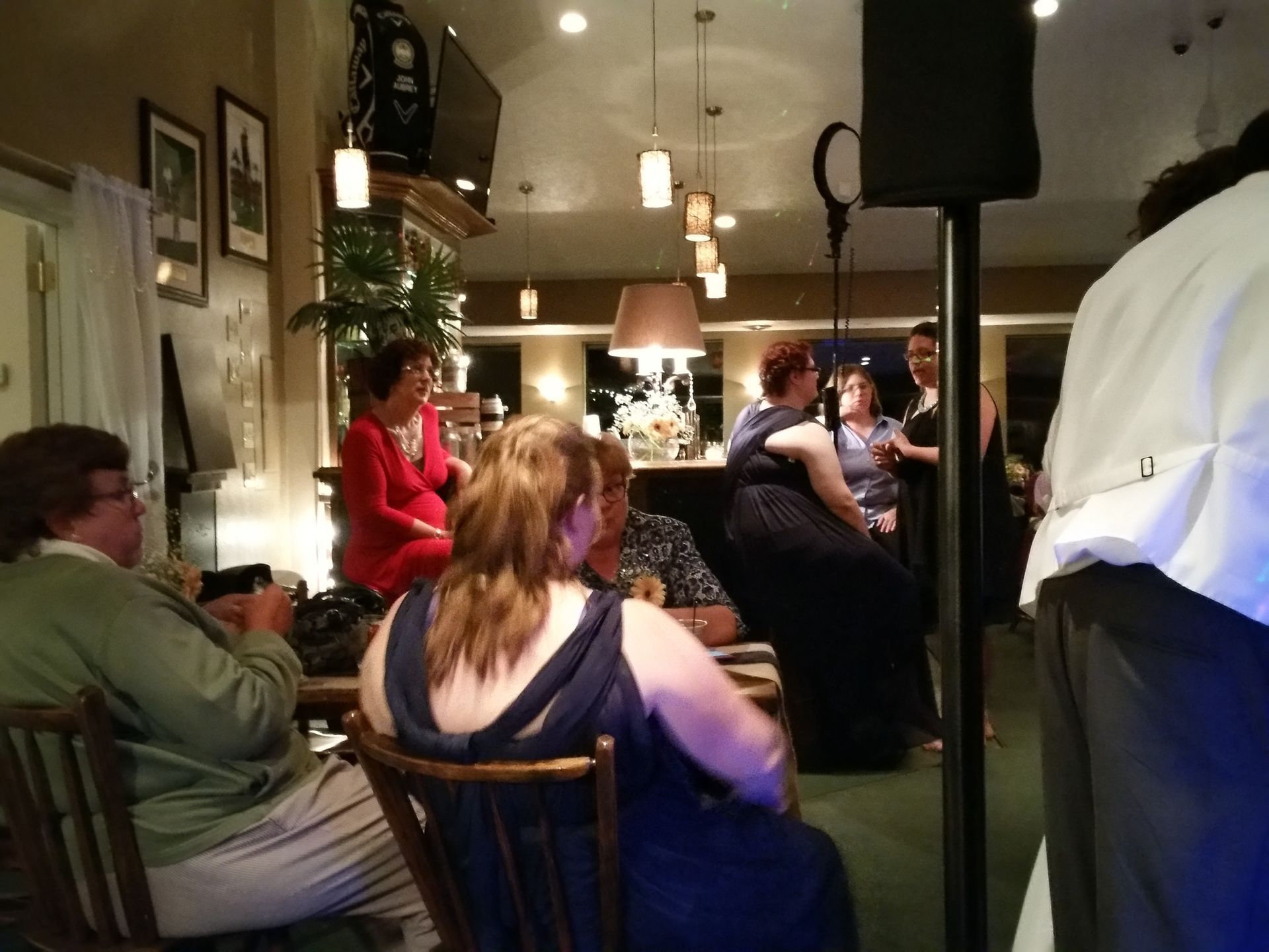 People seated in a cozy café or bar, chatting under warm hanging lights.
