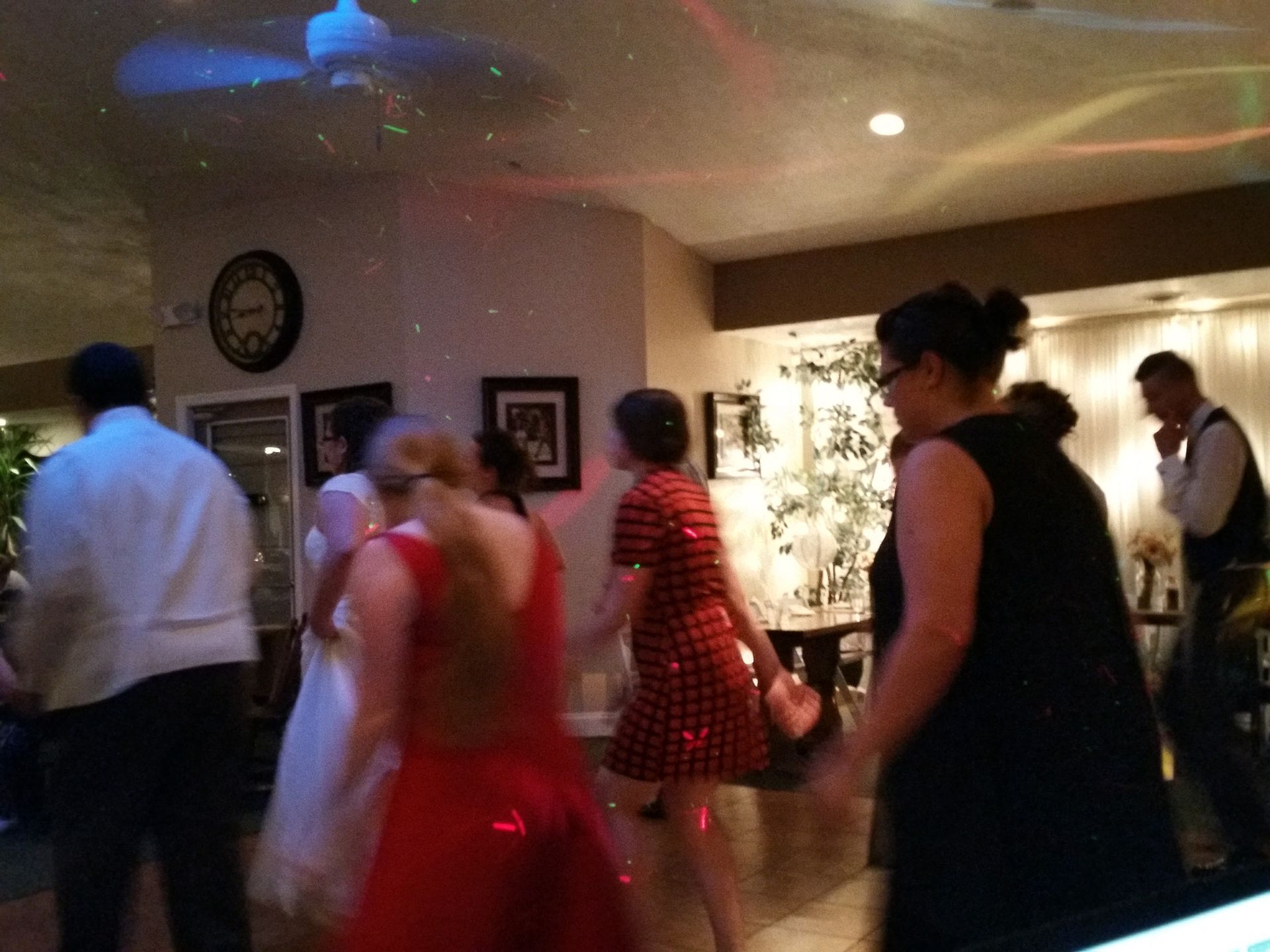 People dancing at an indoor event, with a woman in a red dress in the foreground.