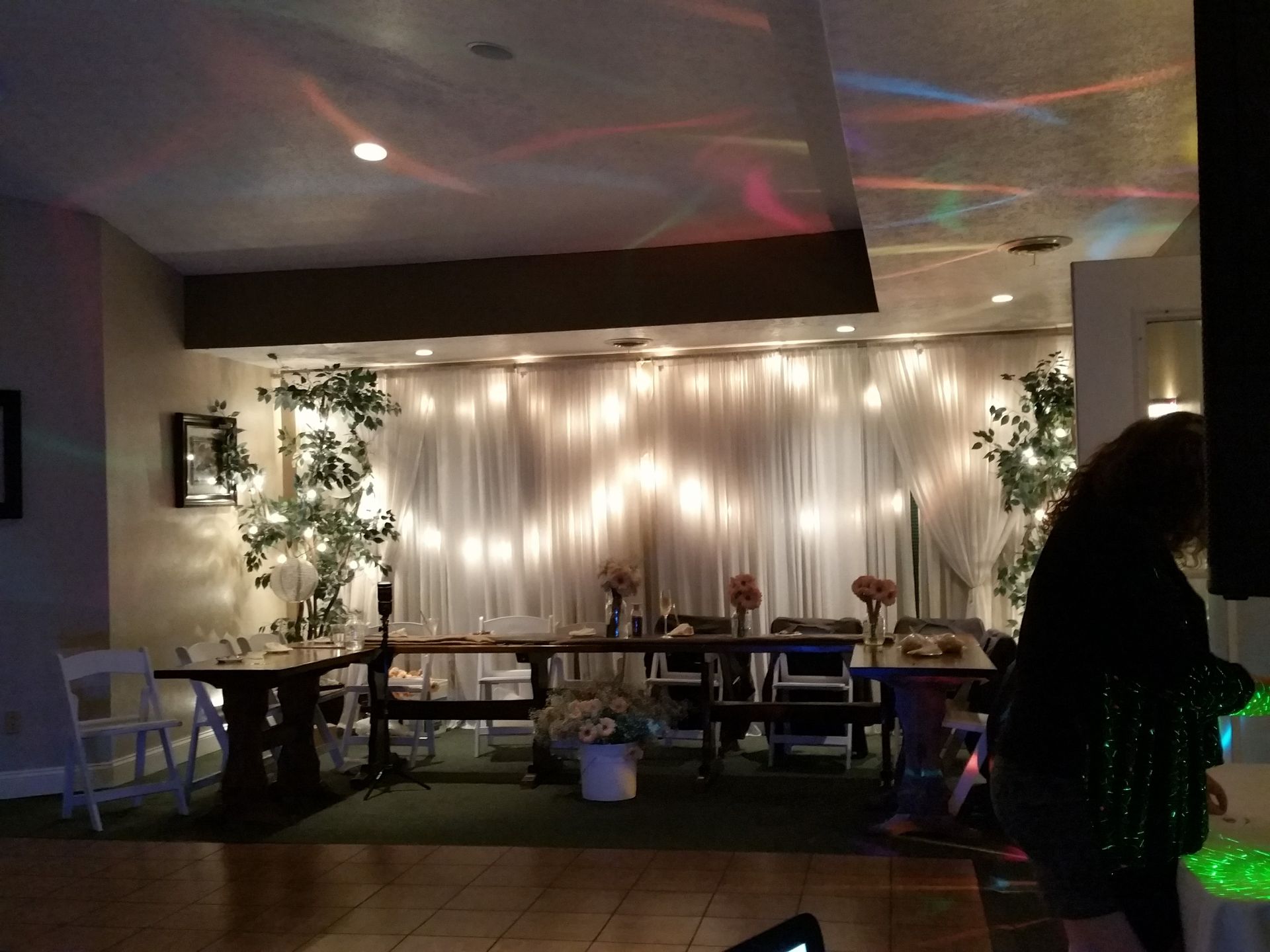Dimly lit lounge with string lights, tables, and a seated person in the foreground