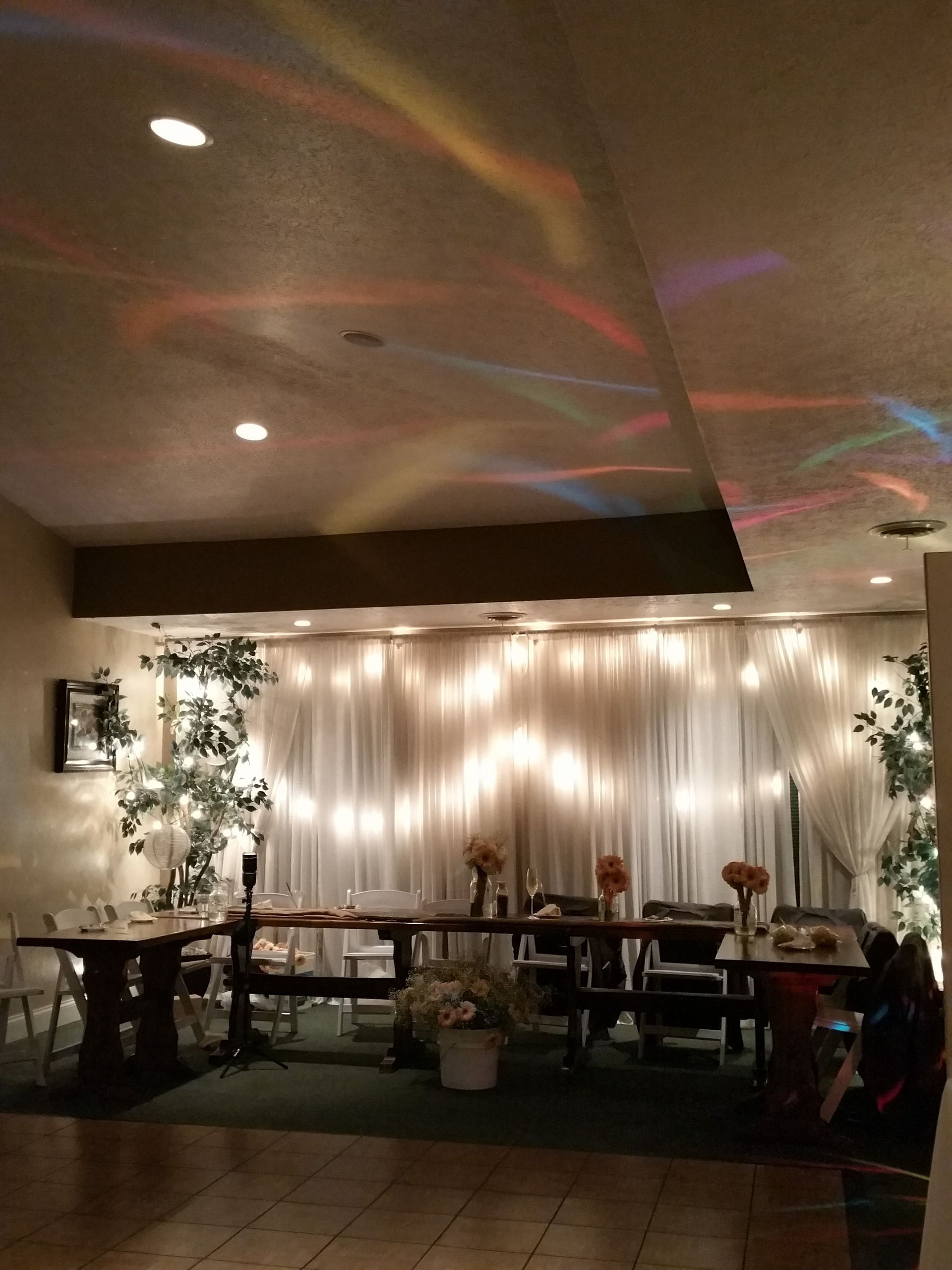Decorated banquet hall with twinkling lights, floral centerpieces, and tables arranged for an event