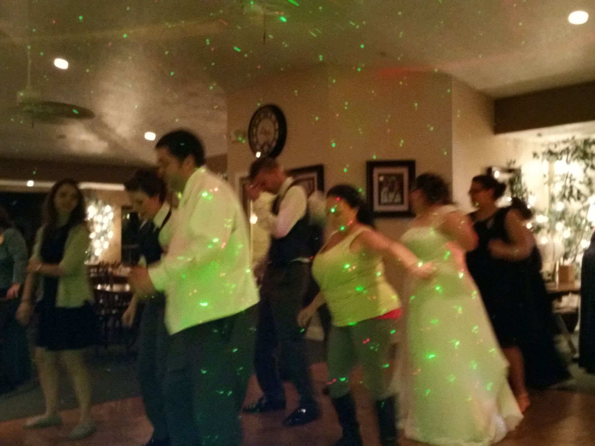 People dancing at a party with green laser lights in a living room