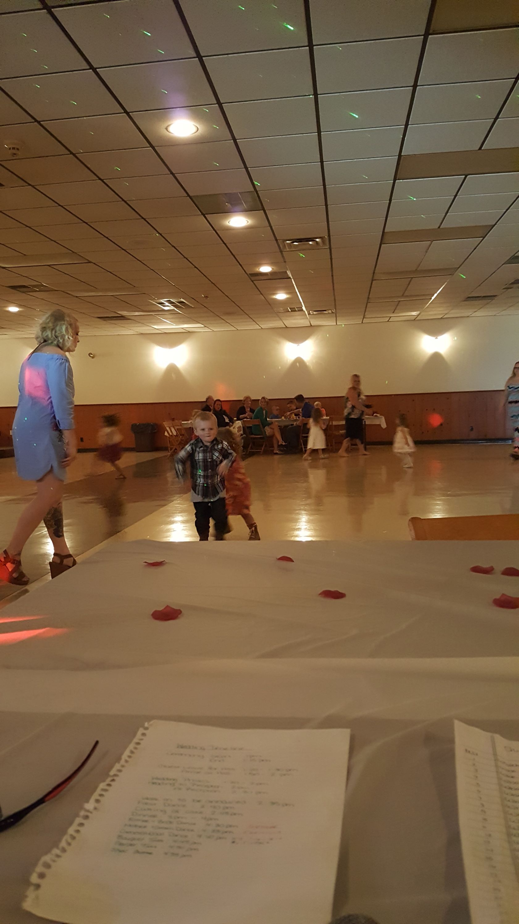 Indoor roller rink with skaters and spectators under ceiling lights, viewed from a table at the rink edge