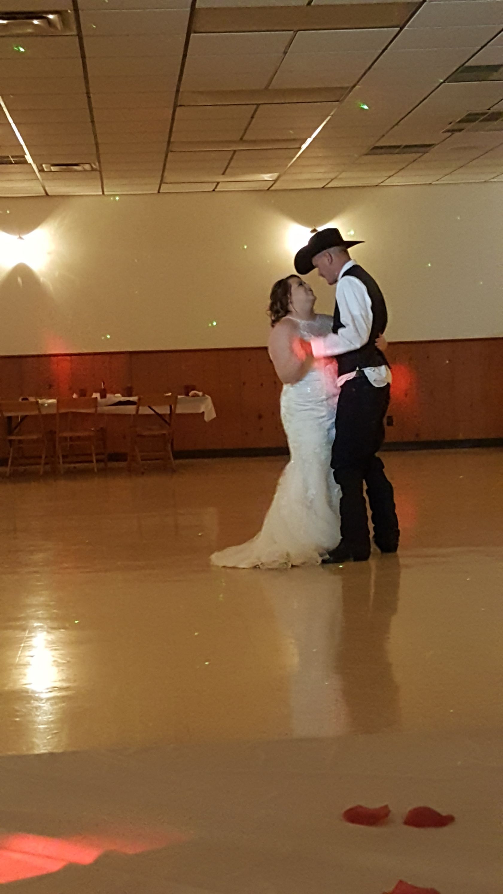 Bride and groom slow dancing at a reception hall under warm ceiling lights